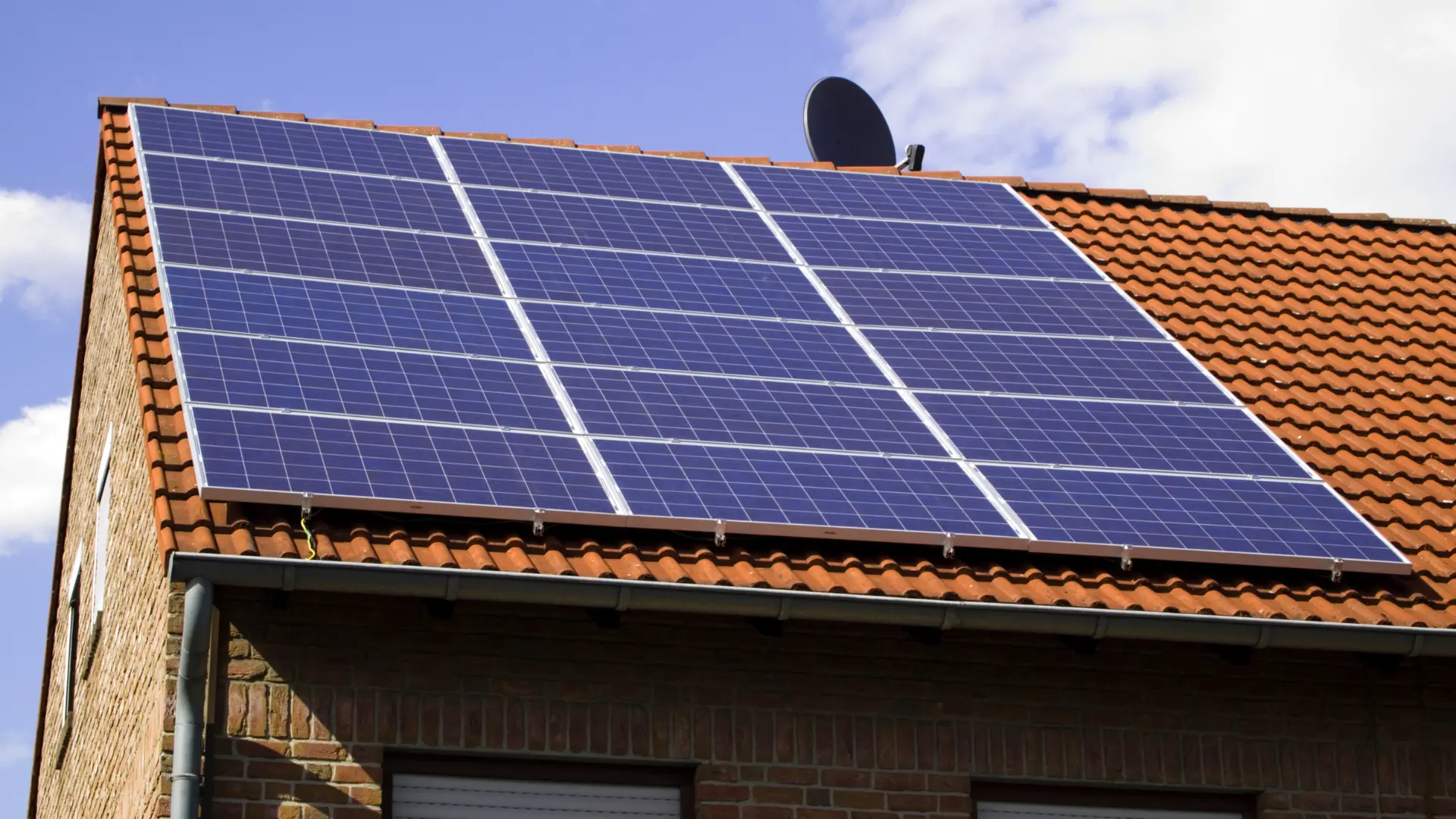 A photovoltaic panel array mounted above a clay-tile roof, shown in PlayaBuilder's solar-energy guide.