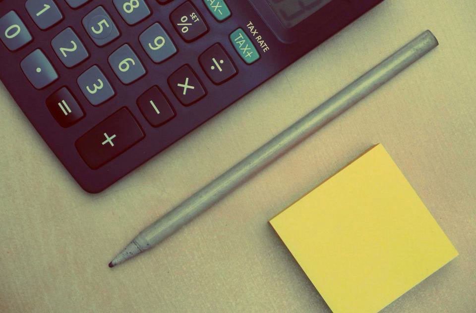 Calculator, pencil and sticky note on a desk