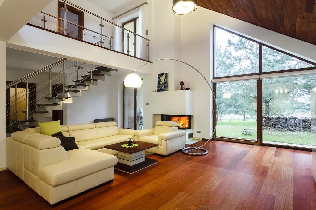 Double-height living room with tall windows, a sectional sofa and open circulation space