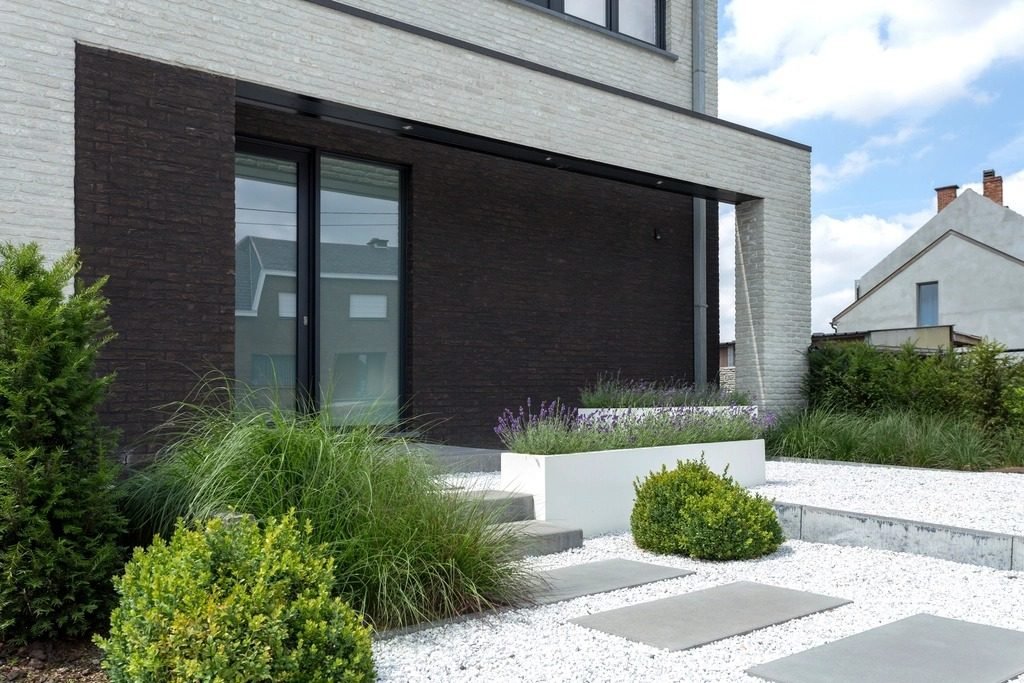 Modern house entrance with a gravel garden, low-maintenance shrubs and concrete steppers