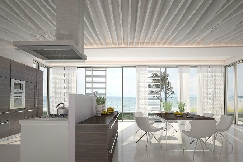 Bright open-plan kitchen with an island and a dining table facing large windows and the sea