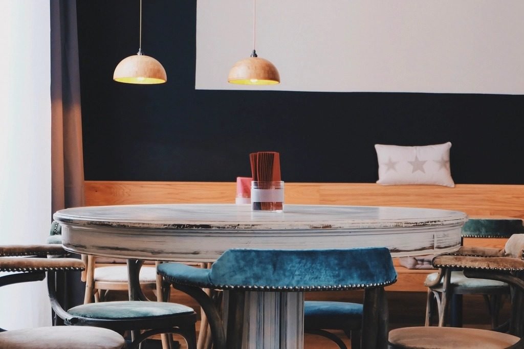 Pendant lamps hung above a round dining table and banquette seating