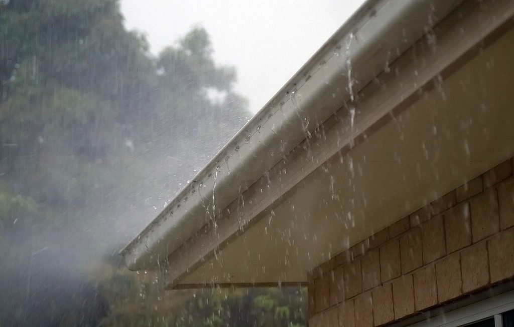 Heavy rain running off the edge of a roof and gutter