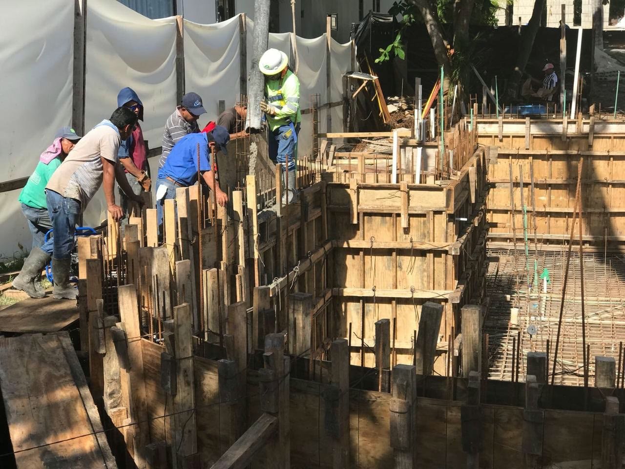 PlayaBuilder crew placing concrete through a pump line into the reinforced timber formwork of a basement near the beach in Playa del Carmen.