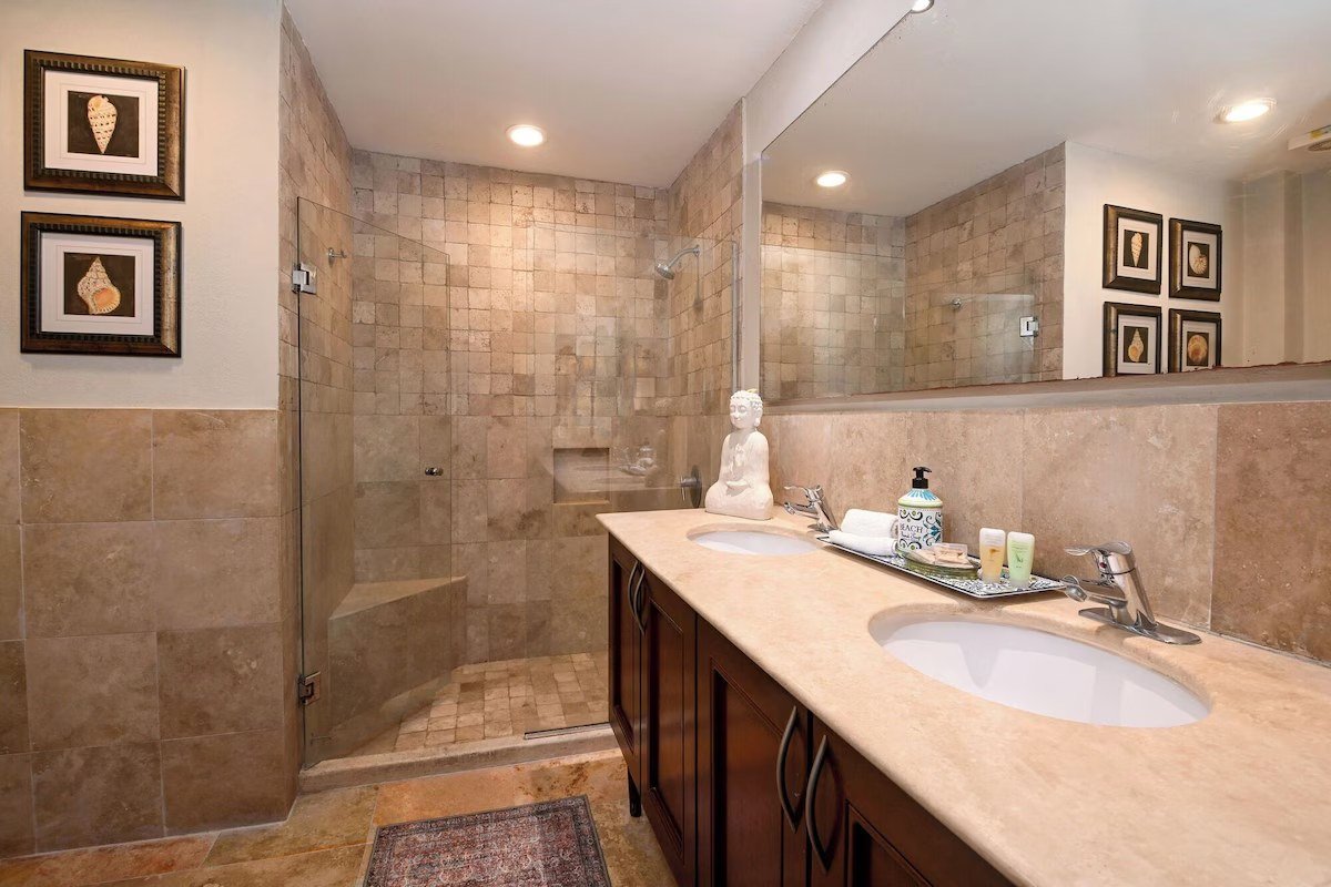 Bathroom with a marble vanity and tiled shower in a beachfront condo in Playa del Carmen.