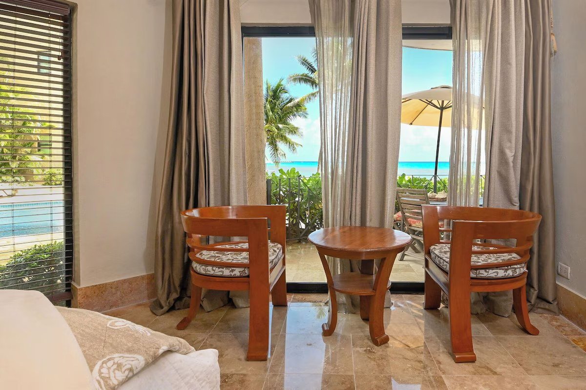 Bedroom with a beach view and dark wood frames in a beachfront condo in Playa del Carmen.