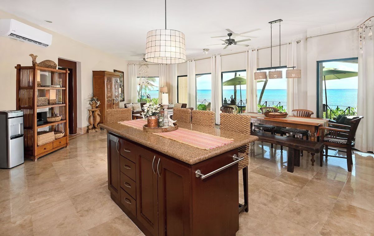 Open kitchen and dining area with travertine floors and ocean views in a beachfront condo in Playa del Carmen.