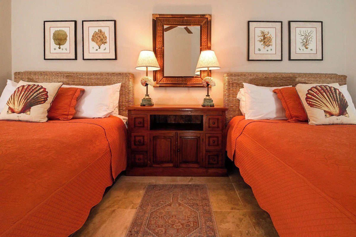 Bedroom with twin beds and wood furniture in a beachfront condo in Playa del Carmen.