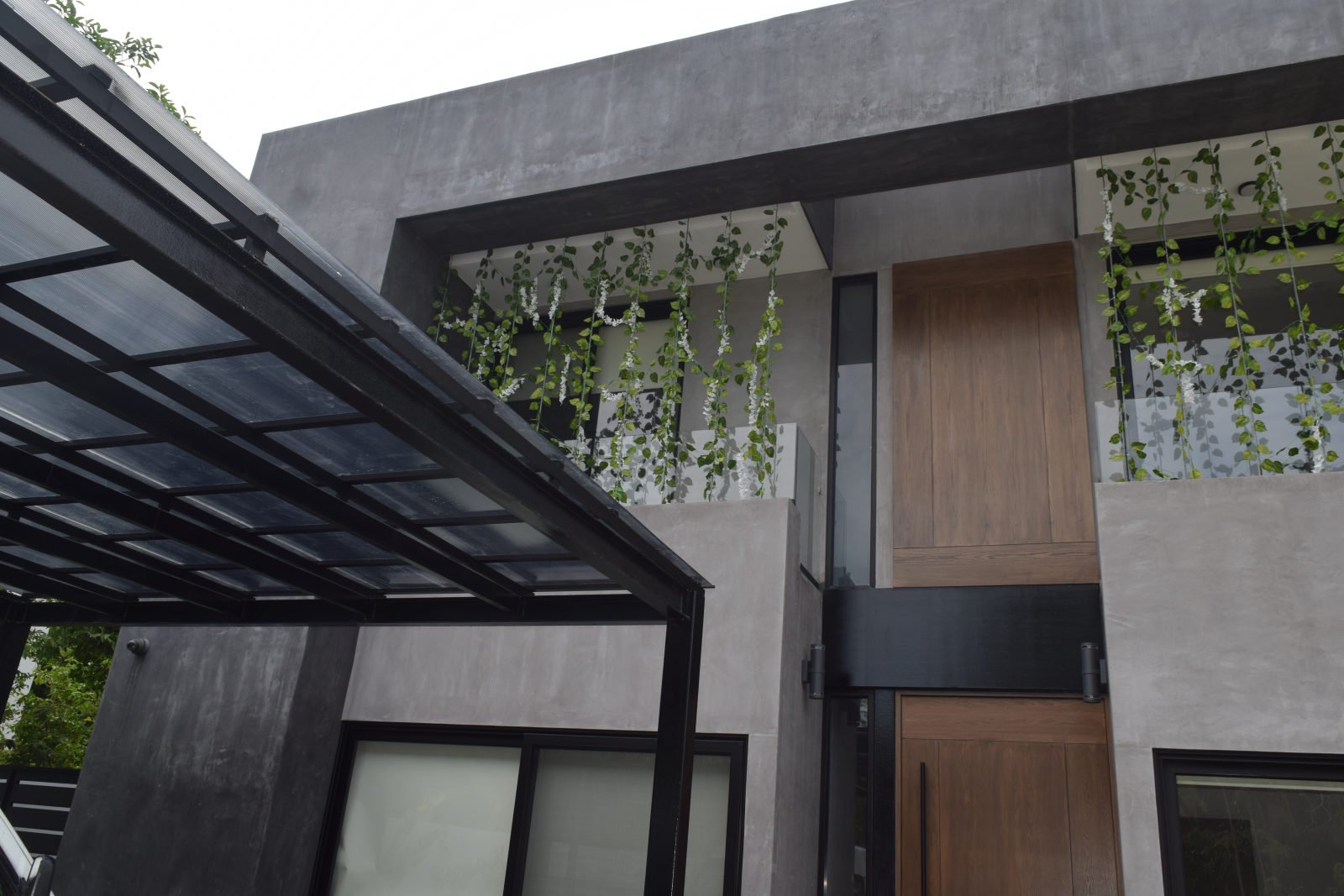 Casa Brisas in Playacar with a timber entrance door, glass walls and a dark metal entrance canopy.