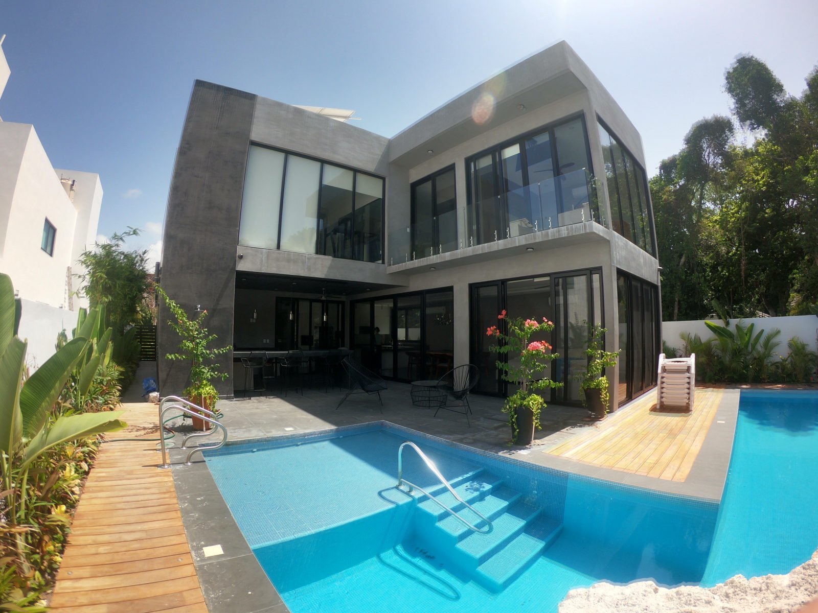 Casa Brisas in Playacar with a swimming pool, timber deck and two-storey facade with large glass openings.