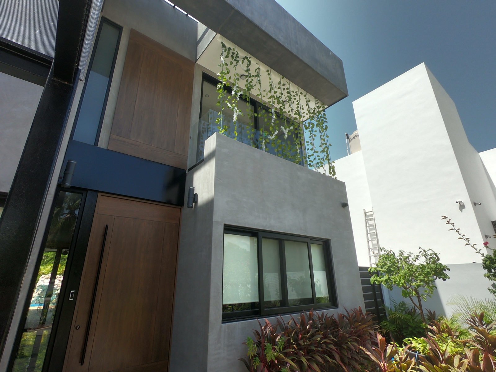 Upper-storey glass balcony, concrete facade and planted entrance at Casa Brisas in Playacar.