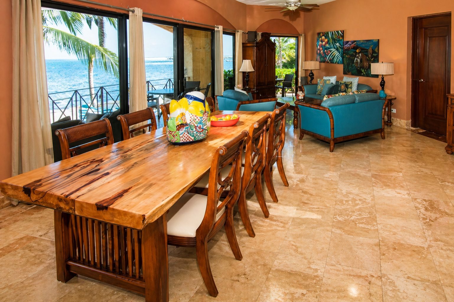Remodeled Luna Encantada condo with a solid-wood dining table, turquoise sofas, marble floors and an ocean-view balcony.